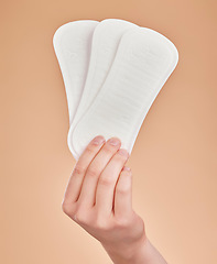 Image showing Hand, sanitary pads and period with a woman in studio on a brown background for female hygiene or care. Lifestyle, and gynecology with a female holding a feminine product for her menstrual cycle