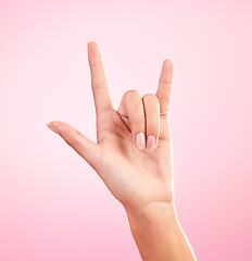 Image showing Hands, closeup and woman in studio with rock and roll sign, gesture or symbol against pink background. Zoom, rebel and girl with rocker emoji for edgy, cool or contemporary, metal or punk aesthetic