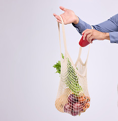 Image showing Hand, shopping and bag for vegetables closeup in studio by background for diet, health or deal in recycle material. Grocery discount, fruit or vegetable for man, healthy food or sustainable lifestyle
