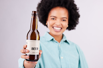 Image showing Hand, beer and advertising with a black woman in studio on a gray background for alcohol promotion. Portrait, bottle and beverage with a female holding a product for celebration or congratulations