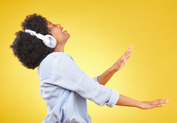 Image showing Black woman, dance with headphones and freedom, music and happiness on yellow studio background. Happy female, carefree and dancing along to radio, audio streaming with fun and energy with technology