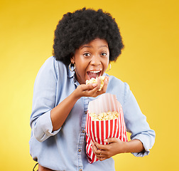 Image showing Happy, food and popcorn with black woman in studio for movie, streaming service and cinema. Crazy, comedy and theatre with female and snack isolated on yellow background for eating, tv and film