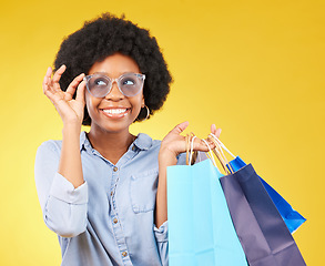 Image showing Fashion, smile and black woman with shopping bags, happy and excited for sale in studio on yellow background. Sunglasses, shopper and girl customer cheerful after boutique, retail or store discount