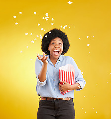 Image showing Happy, throwing and popcorn with black woman in studio for movie, streaming service and cinema. Laugh, funny and theatre with female and snack isolated on yellow background for food, tv and film