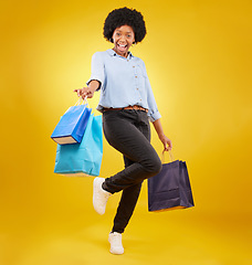 Image showing Black woman with shopping bag, happy with fashion and retail in portrait on yellow studio background. Happiness, female with discount and sale at boutique with designer brand, carefree and mockup