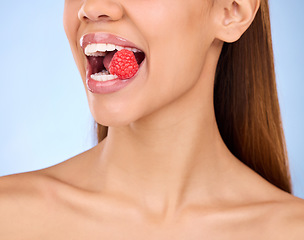 Image showing Mouth, beauty and strawberry with a model woman in studio on a blue background closeup biting a fruit. Food, health and nutrition with a female eating a berry for antioxidants or diet benefits