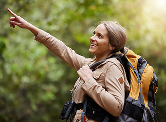 Image showing Hiking, pointing or happy woman in nature, forest or wilderness for a trekking adventure. Freedom, backpack excited female hiker walking in a natural park or woods for exercise or wellness on holiday