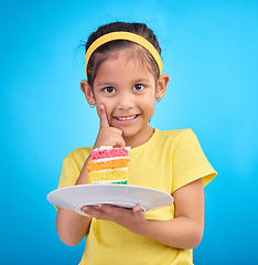 Image showing Birthday cake, portrait and young girl with sweet in studio eating icing for party event dessert. Celebration, rainbow food and hungry kid in a isolated and blue background youth ready to celebrate