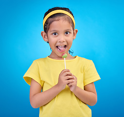 Image showing Young girl, portrait and lollipop with a student feeling happy with a smile and blue background. Isolated, cute and adorable child face with happiness, joy and cheerful from dessert and sweet