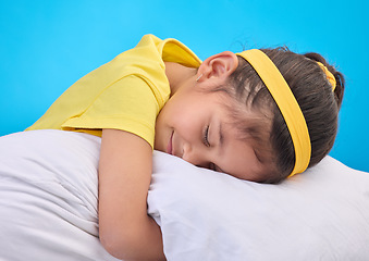 Image showing Calm young girl, pillow and sleep in a studio feeling tired, fatigue and ready for dreaming. Isolated, blue background and happy little child with pillows and closed eyes for sleeping, rest and nap