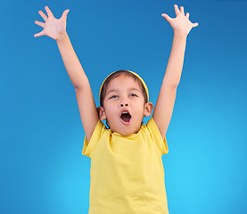 Image showing Child, goal cheer and studio with a little girl feeling happy with energy and celebration. Isolated blue background and young kid with arms in the air cheering crazy and yelling with happiness