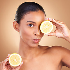 Image showing Indian woman, beauty and skincare with lemon in studio for health, wellness or fruit by brown background. Asian model girl, young or happy with natural citrus fruits for health, cosmetic or skin glow