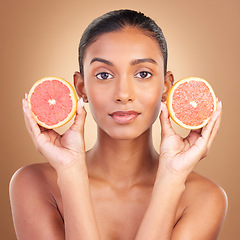Image showing Indian woman, grapefruit and studio portrait for beauty, health or wellness with fruit by brown background. Asian young model and girl with organic citrus fruits for health, cosmetic and skin glow