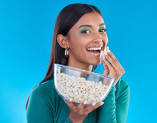 Image showing Black woman, studio portrait and eating popcorn, smile or makeup for beauty, aesthetic and blue background. Gen z model, happiness and healthy corn snack for movies with cosmetics, fashion or excited