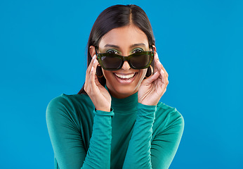 Image showing Sunglasses, fashion and woman with cool style and smile feeling happy and excited isolated in studio blue background. Portrait, young and model or trendy gen z female with stylish beauty