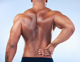 Image showing Black man, back pain and injury with fitness and health, medical problem and aching body in studio. Emergency, muscle tension and male athlete with joint ache from workout on blue background