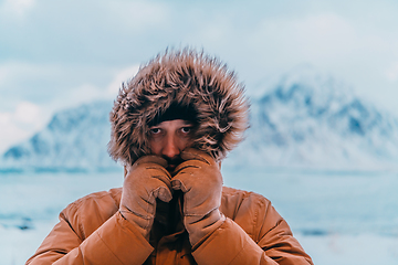 Image showing Headshot photo of a man in a cold snowy area wearing a thick brown winter jacket and gloves. Life in cold regions of the country.