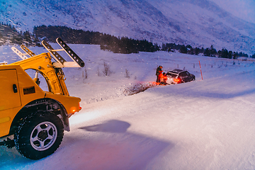 Image showing The roadside assistance service pulling the car out of the canal. An incident on a frozen Scandinavian road.