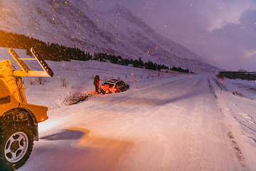 Image showing The roadside assistance service pulling the car out of the canal. An incident on a frozen Scandinavian road.