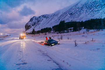 Image showing The roadside assistance service pulling the car out of the canal. An incident on a frozen Scandinavian road.