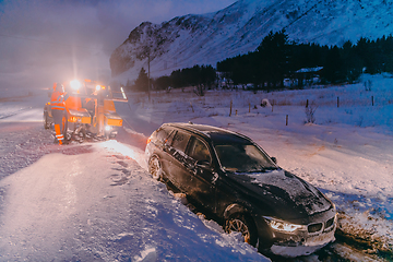 Image showing The roadside assistance service pulling the car out of the canal. An incident on a frozen Scandinavian road.