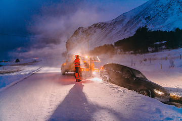 Image showing The roadside assistance service pulling the car out of the canal. An incident on a frozen Scandinavian road.