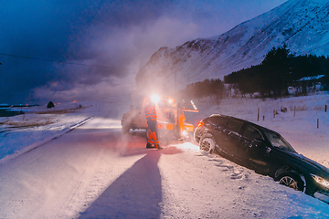 Image showing The roadside assistance service pulling the car out of the canal. An incident on a frozen Scandinavian road.