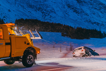 Image showing The roadside assistance service pulling the car out of the canal. An incident on a frozen Scandinavian road.