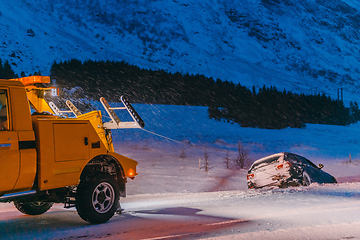 Image showing The roadside assistance service pulling the car out of the canal. An incident on a frozen Scandinavian road.