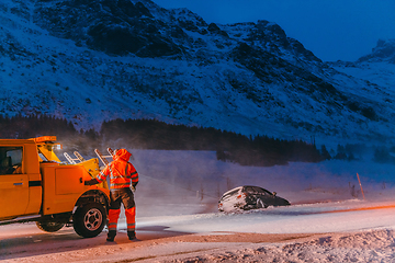 Image showing The roadside assistance service pulling the car out of the canal. An incident on a frozen Scandinavian road.