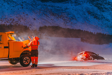 Image showing The roadside assistance service pulling the car out of the canal. An incident on a frozen Scandinavian road.