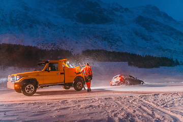 Image showing The roadside assistance service pulling the car out of the canal. An incident on a frozen Scandinavian road.