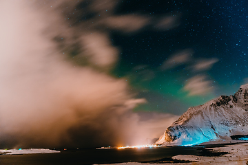 Image showing Amazing display of northern lights seen in the north with a bright green band dancing across the sky with a stunning log cabin lodge below.