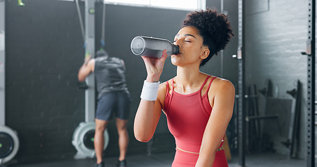 Image showing Black woman, rest and drinking water with bottle for fitness, wellness and health in gym. Young female, athlete or healthy lady relax, being thirsty after practice or training for exercise or workout