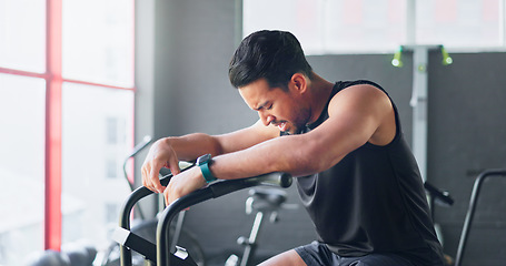 Image showing Fitness, bicycle and man tired of cycling for cardio, exercise and training at gym. Wellness, workout and strong Asian man breathing and sweating thinking of motivation and goal on a bike machine