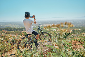 Image showing Cycling, fitness and man on a bicycle with phone for picture, photography or photo in nature. Cyclist, workout and social media health influencer live streaming for blog, website or profile picture