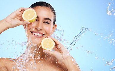 Image showing Beauty, lemon and water splash with portrait of woman in studio for natural cosmetics, nutrition and detox. Glow, fruits and hydration with female on blue background for diet, clean face and skincare