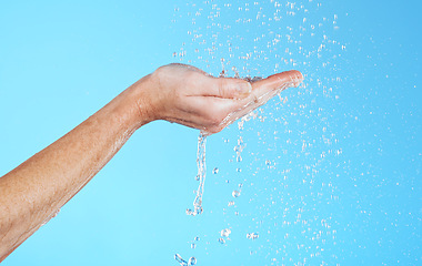 Image showing Hands, cleaning and water in a studio for skincare, safety and healthcare from virus. Isolated, blue background and hand wash for hygiene wellness and sanitary protection with liquid stream to clean