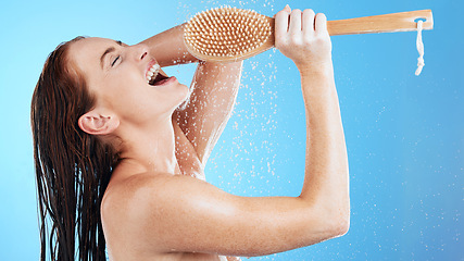 Image showing Shower karaoke, skincare and woman with happiness singing in a studio. Bathroom, music and happy female model with isolated blue background and cleaning brush for beauty routine and wellness