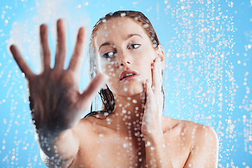 Image showing Shower, water drops and woman hand doing skin cleaning, wellness and beauty routine in bathroom. Isolated, blue background and studio with a young female doing hair care and dermatology facial