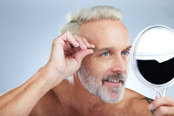 Image showing Senior man, tweezers and mirror check in a studio doing hair cleaning and grooming. Wellness, dermatology and beauty routine of a mature male model care with grey background and steel tools for face