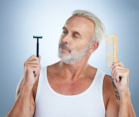 Image showing Senior man, shaver and comb thinking for grooming, skincare or hair removal against studio background. thoughtful mature male holding razor blade and brush for haircare, cosmetics or facial treatment