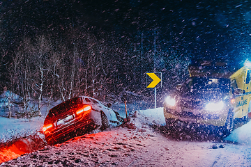 Image showing The roadside assistance service pulling the car out of the canal. An incident on a frozen Scandinavian road.