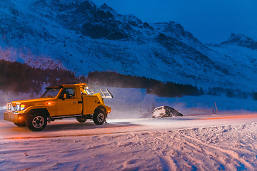 Image showing The roadside assistance service pulling the car out of the canal. An incident on a frozen Scandinavian road.