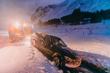 Image showing The roadside assistance service pulling the car out of the canal. An incident on a frozen Scandinavian road.