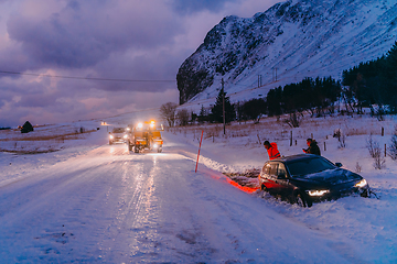 Image showing The roadside assistance service pulling the car out of the canal. An incident on a frozen Scandinavian road.