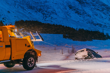 Image showing The roadside assistance service pulling the car out of the canal. An incident on a frozen Scandinavian road.