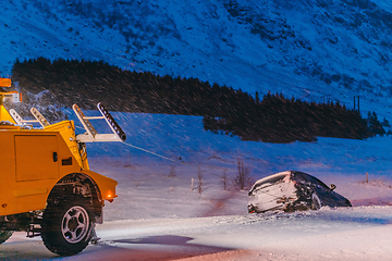 Image showing The roadside assistance service pulling the car out of the canal. An incident on a frozen Scandinavian road.