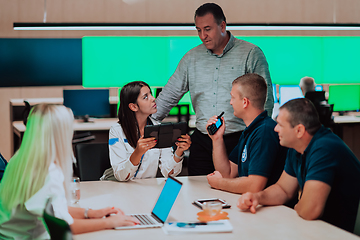 Image showing Group of security guards sitting and having briefing In the system control room They're working in security data center surrounded by multiple Screens