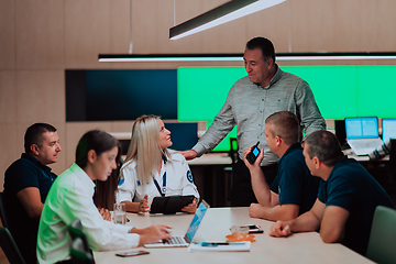 Image showing Group of security guards sitting and having briefing In the system control room They're working in security data center surrounded by multiple Screens